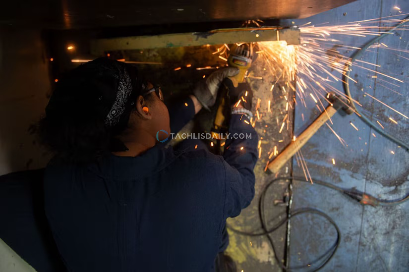 Sparks fly as a sailor grinds steel.